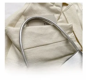 Detail of silver metallic handbag featuring large buckle and smooth rounded shoulder strap
