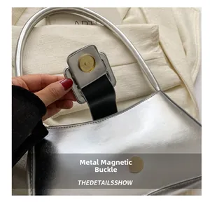 Close-up of golden magnetic hardware buckle on metallic silver handbag