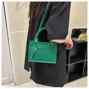 Detail einer neongrünen Mini-Handtasche mit Kroko-Prägung, Fransenquaste und Rundgriff