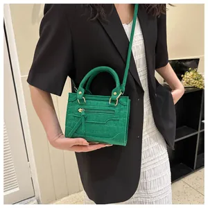 Grüne Mini-Handtasche mit Krokodil-Prägung und stilvollem Quasten-Detail in Nahaufnahme