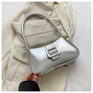 Detail of silver metallic shoulder bag with large square buckle on a beige blazer