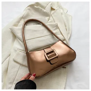 Close-up of metallic copper baguette bag with large square buckle on a stylish suit