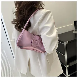Detailed view of metallic pink baguette bag with large buckle on a model shoulder