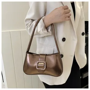 Macro shot of metallic bronze underarm bag with oversized square buckle on white blazer