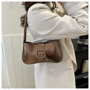 Detailed close-up of a bronze baguette bag featuring a large metallic square buckle