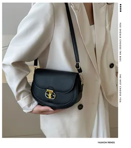 Detail of black litchi grain leather saddle bag featuring a gold horseshoe twist lock
