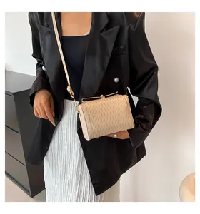 Dettaglio della mini borsa a tracolla beige chiaro con texture a onde e fibbia dorata su modella