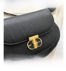 Close-up of litchi pattern leather saddle bag with T-shaped golden metal lock detail