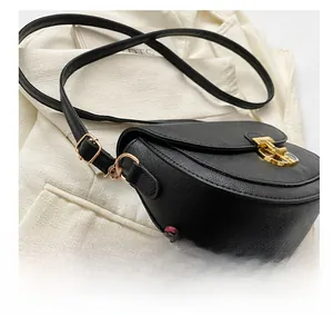 Detail of black saddle bag featuring lychee grain leather and gold metal buckle
