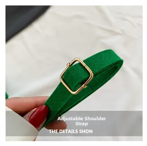 Detailed macro view of adjustable green felt shoulder strap with gold metal buckle