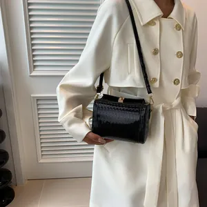 Borsa a tracolla retrò nera plissettata in pelle con fibbia dorata su trench bianco
