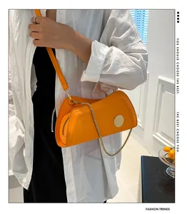 Detailansicht der leuchtend orangefarbenen Ledertasche mit Goldkette und kurvigem Design