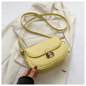 Detail of lime yellow leather saddle bag with gold T-lock on white textured blazer