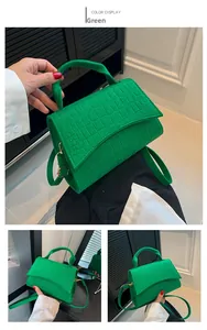 Detail of green crocodile-textured felt crossbody bag with gold metal buckle