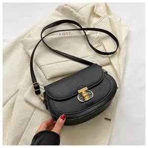 Detail of the golden metal buckle and cross-grain leather texture on a black saddle bag