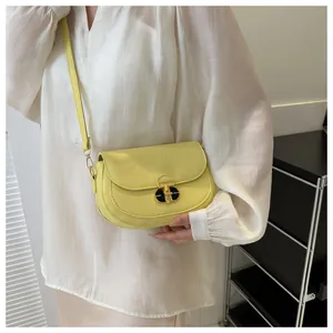 Detail of yellow saddle bag showing golden hardware buckle and leather texture on a model