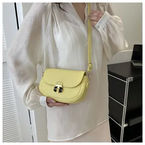 Detailed close-up of a bright yellow saddle bag featuring a round golden metallic lock