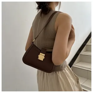 Borsa sottobraccio classica marrone scuro con fibbia dorata indossata a spalla