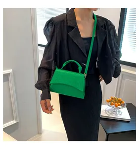 Close-up of vibrant green crocodile pattern leather crossbody bag on a female model