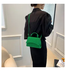 Detail view of bright green crocodile pattern felt crossbody bag on a model in black