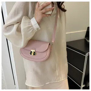 Close-up of pink saddle bag featuring a unique black and gold metal twist lock
