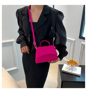 Detailed side view of a magenta crossbody bag with gold hardware and a top handle