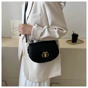 Detail of black saddle bag with lychee texture leather and golden geometric lock buckle