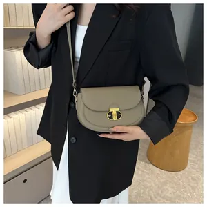 Detailed close-up of textured leather saddle bag with gold T-shaped metal lock closure