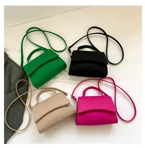 Detailed macro of crocodile pattern felt crossbody bags in green, black, beige and rose red