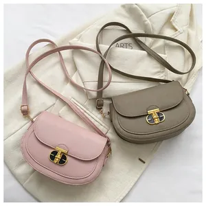 Detail of pink and taupe saddle bags featuring elegant golden T-shaped metal twist locks