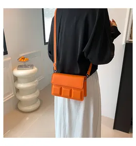 Detail van oranje crossbodytas met 3D-geometrisch ontwerp en gladde lederen textuur