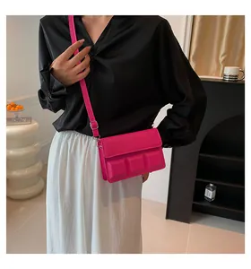 Detail van rozerode crossbodytas met 3D-geëmbosseerd geometrisch patroon