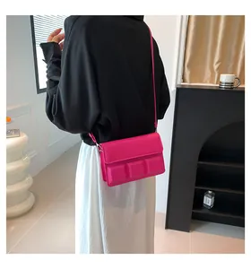 Detail van roze crossbodytas met reliëf 3D-blokken op de flap en smalle schouderriem