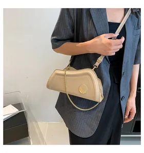 Detail der beigen Schultertasche mit asymmetrischem Design, Golddekor und Kettenriemen