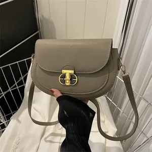 Solid color textured saddle bag with gold T-shaped lock and lychee grain leather finish