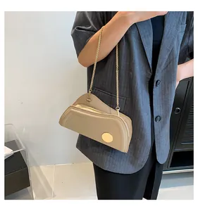 Detail der khakifarbenen asymmetrischen Achseltasche mit Goldkette auf grauem Blazer