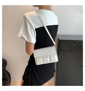 Detail van witte crossbodytas met uniek geometrisch 3D-reliëfpatroon op de klepsluiting