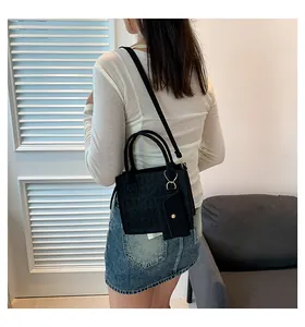 Détail d'un sac à main en feutre noir texturé avec motifs floraux gaufrés et mini pochette