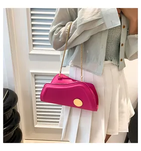 Detailaufnahme einer trendigen rosaroten Schultertasche mit goldener Kette am Model