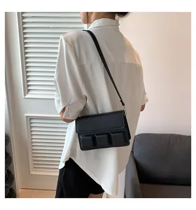 Detail van zwarte crossbodytas met 3D-geometrische vormen gedragen op wit shirt
