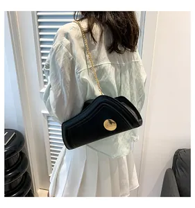 Nahaufnahme der asymmetrischen schwarzen Ledertasche mit goldenem Metallbeschlag und Kette
