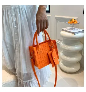 Détail du sac à main en feutre orange vif avec texture géométrique en relief et mini pochette