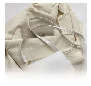 Detail of adjustable shoulder strap and gold hardware on white minimalist crossbody bag