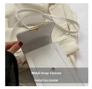 Detail of white leather bag featuring a gold magnetic buckle and refined flap closure