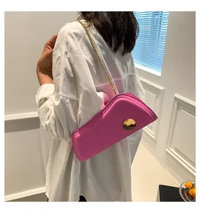 Details einer rosafarbenen Schultertasche mit goldener Schnalle und Kettenriemen