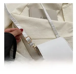 Detail of adjustable shoulder strap with premium golden metal hooks on white leather bag