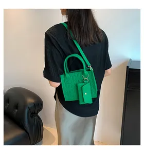 Détail d'un ensemble sac à main vert gaufré en feutre avec pochette assortie et boucle dorée
