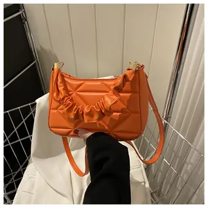 Makro-Detail der orangen gesteppten Tragetasche mit Raffgriff und goldenen Metallteilen