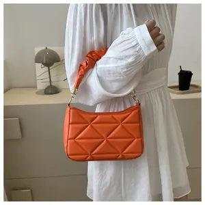 Detail der orangefarbenen PU-Tasche mit 3D-Dreieckssteppung und gerafftem Schultergurt