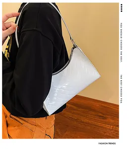 Close-up of white patent leather shoulder bag with V-shaped quilting and silver zipper